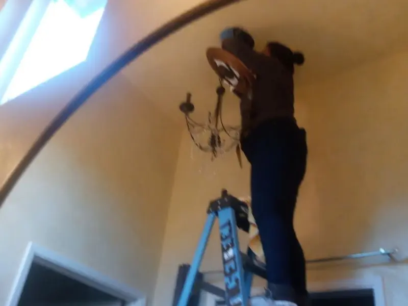 Electrician installing a chandelier in a French Camp residence